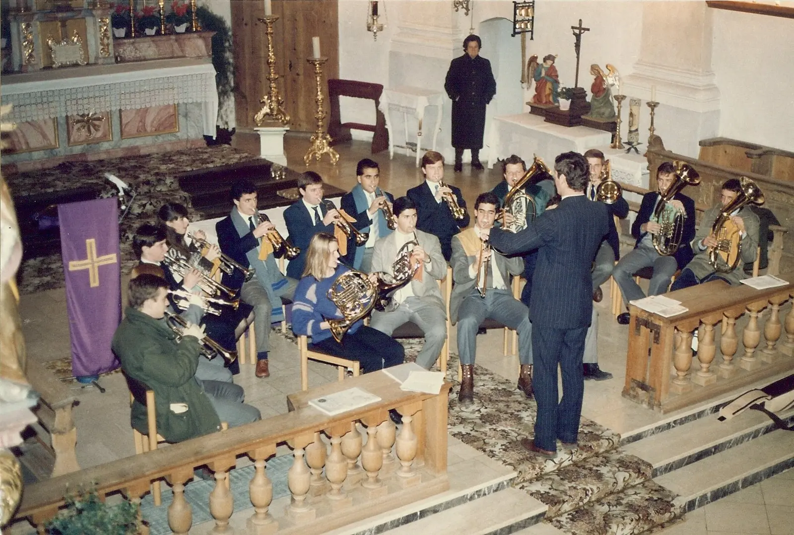 El coro tocando sentado dentro de una iglesia católica bávara, frente a un altar dorado