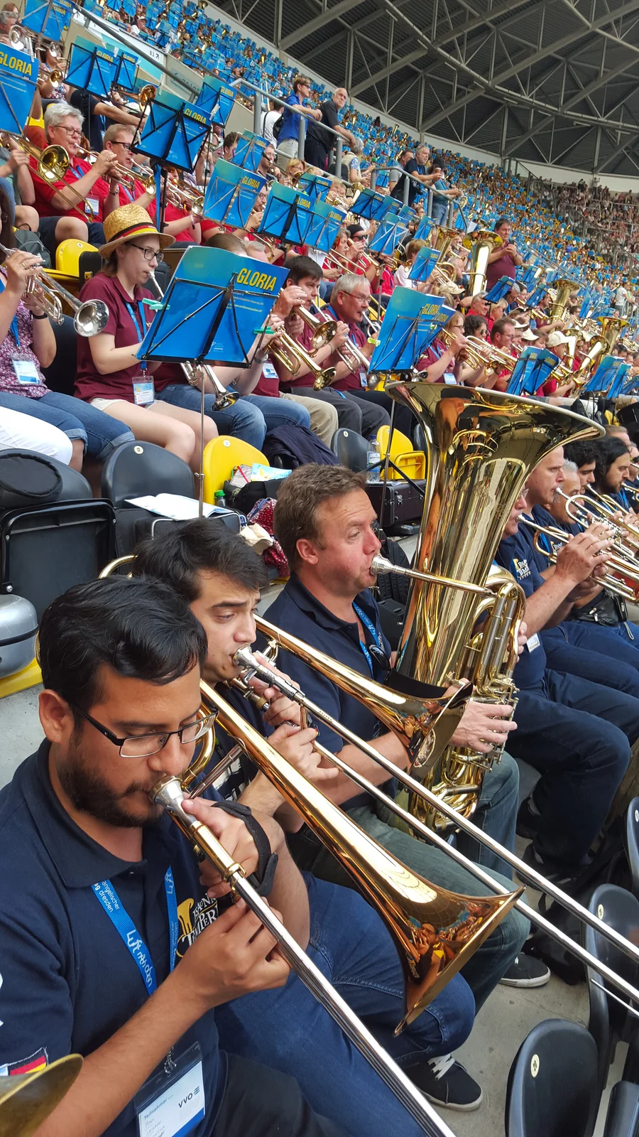 Hans, Axel y Peta tocando entre miles de instrumentistas en las tribunas del Stadion Dresden, rodeados de atriles azules