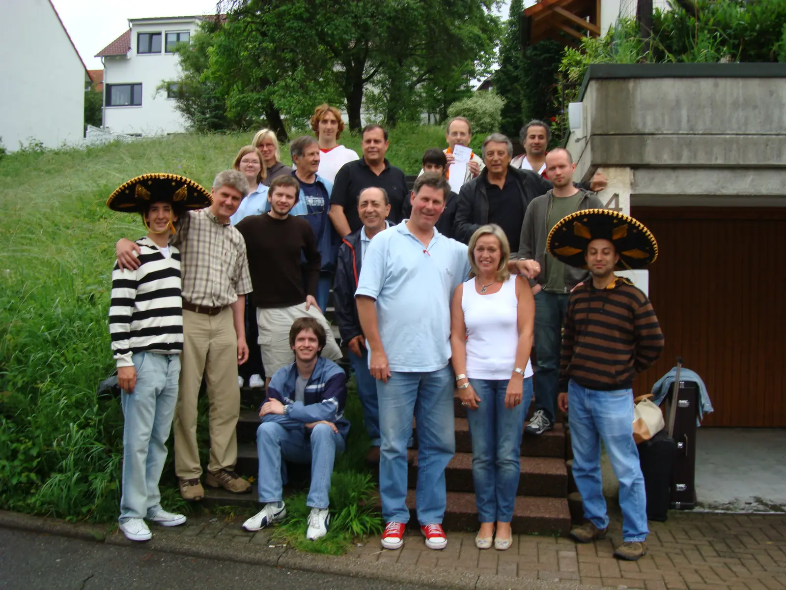 El grupo argentino y alemán posando en la escalera de una casa en Alemania, dos de ellos con grandes sombreros charro negros y dorados