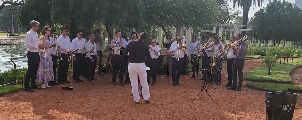 Blechbläserensemble beim Spiel im Freien am Ufer eines Sees im Rosedal von Palermo, der Dirigent mit dem Rücken zur Kamera in Schwarz und Weiß gekleidet