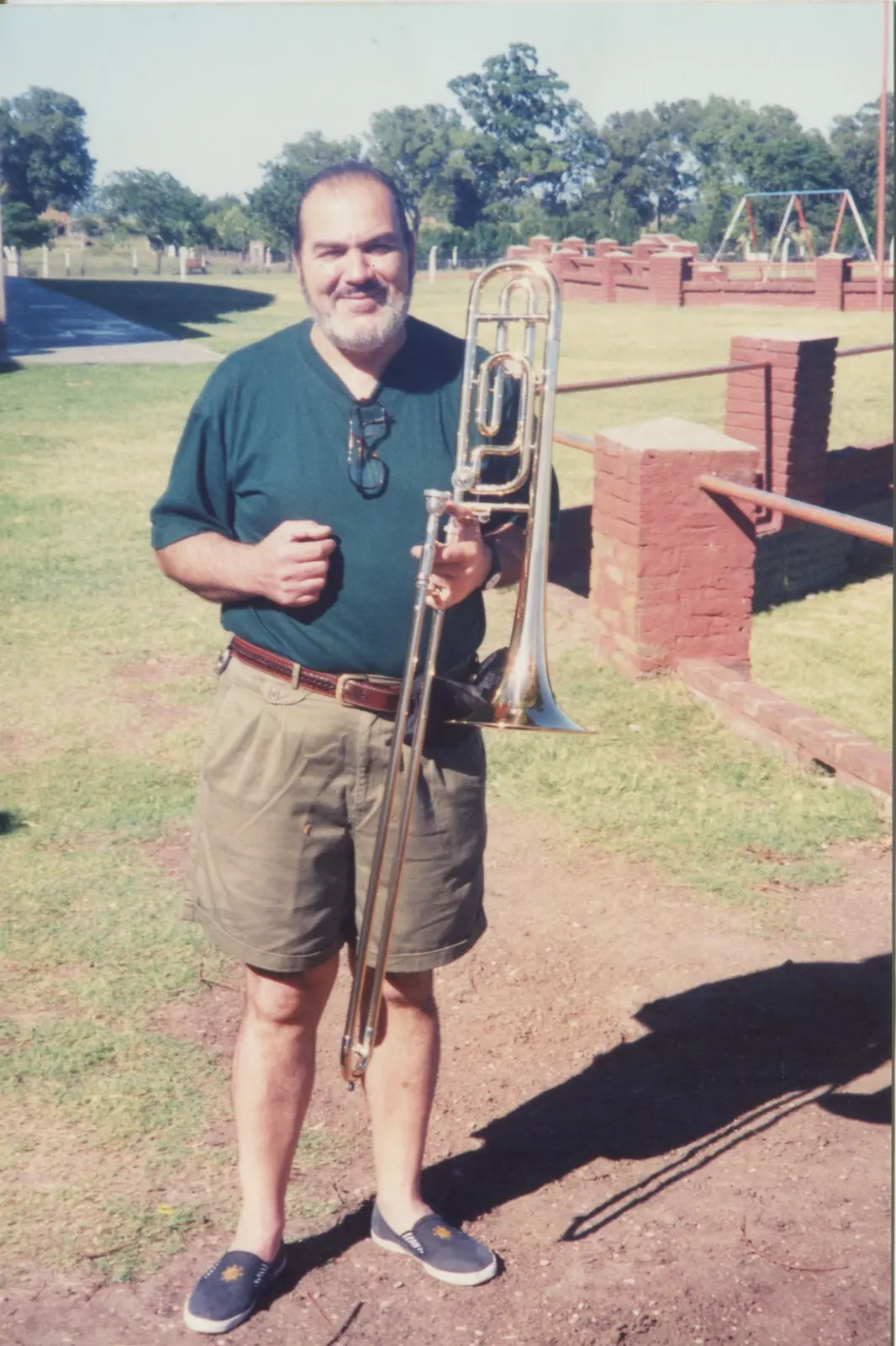 Gaspar Licciardone joven, de remera verde y bermudas, sosteniendo su trombón en el patio de un hogar en Entre Ríos, enero de 1996