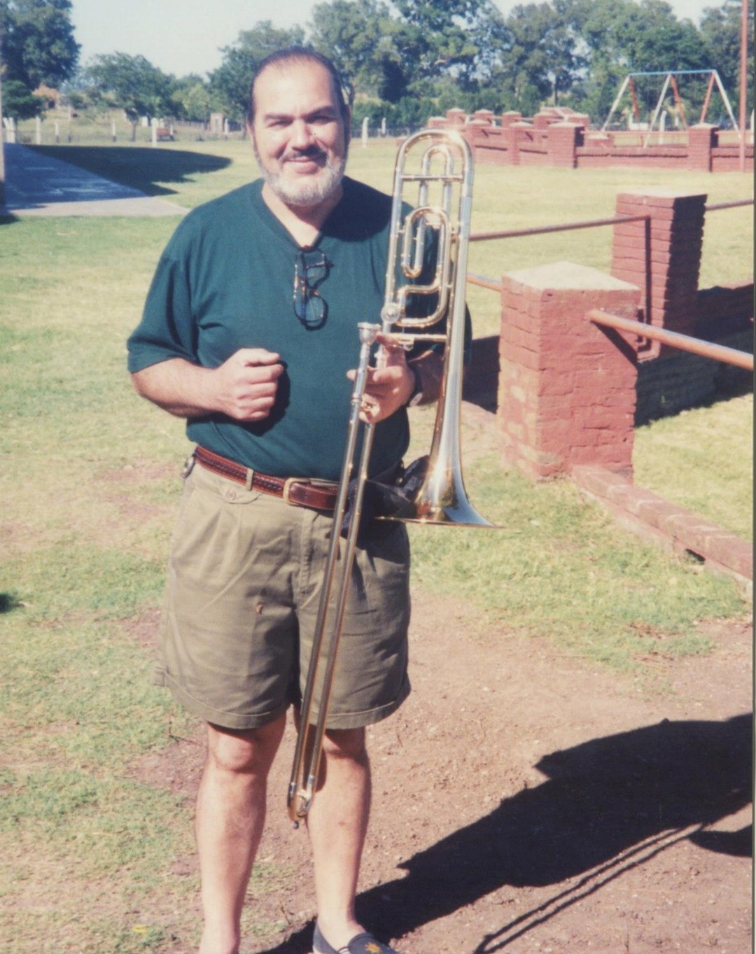 Gaspar Licciardone joven, de remera verde, sosteniendo un trombón al aire libre en Ramírez, enero de 1996
