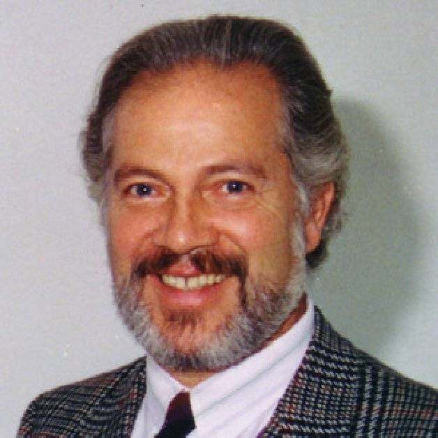 Retrato en color de Güelfo Nalli sonriendo, pelo y barba canosos, saco de tweed a cuadros, camisa blanca y corbata oscura