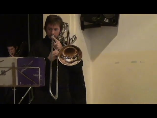 Willi Mengel de pie, tocando el trombón bajo como solista, frente al atril