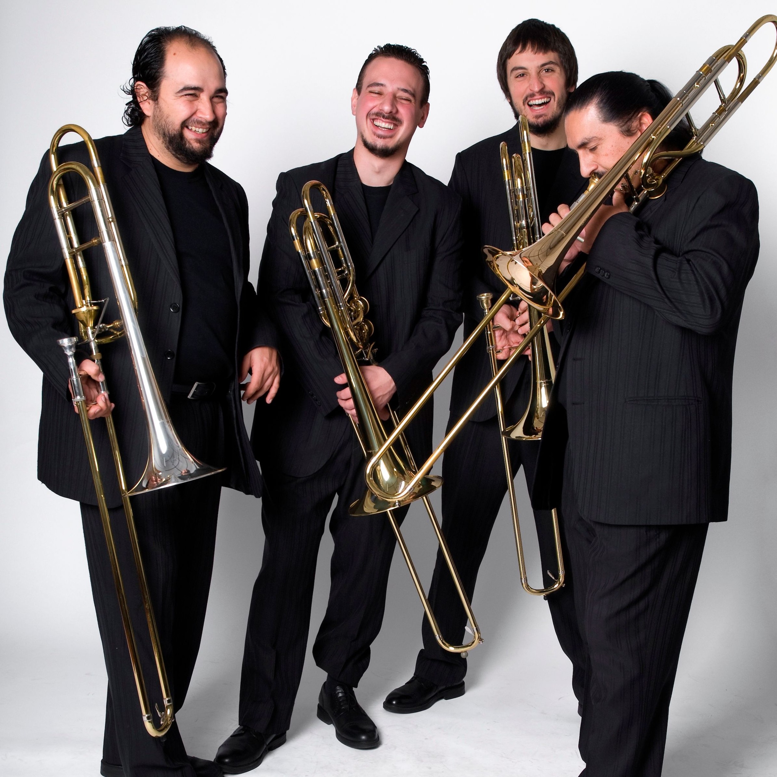 Die vier Mitglieder von Viento Sur Trombones lachend, mit ihren Posaunen, vor weißem Hintergrund