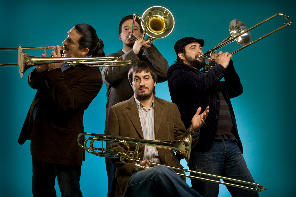 Viento Sur Trombones vor türkisem Hintergrund, drei spielend und einer sitzend