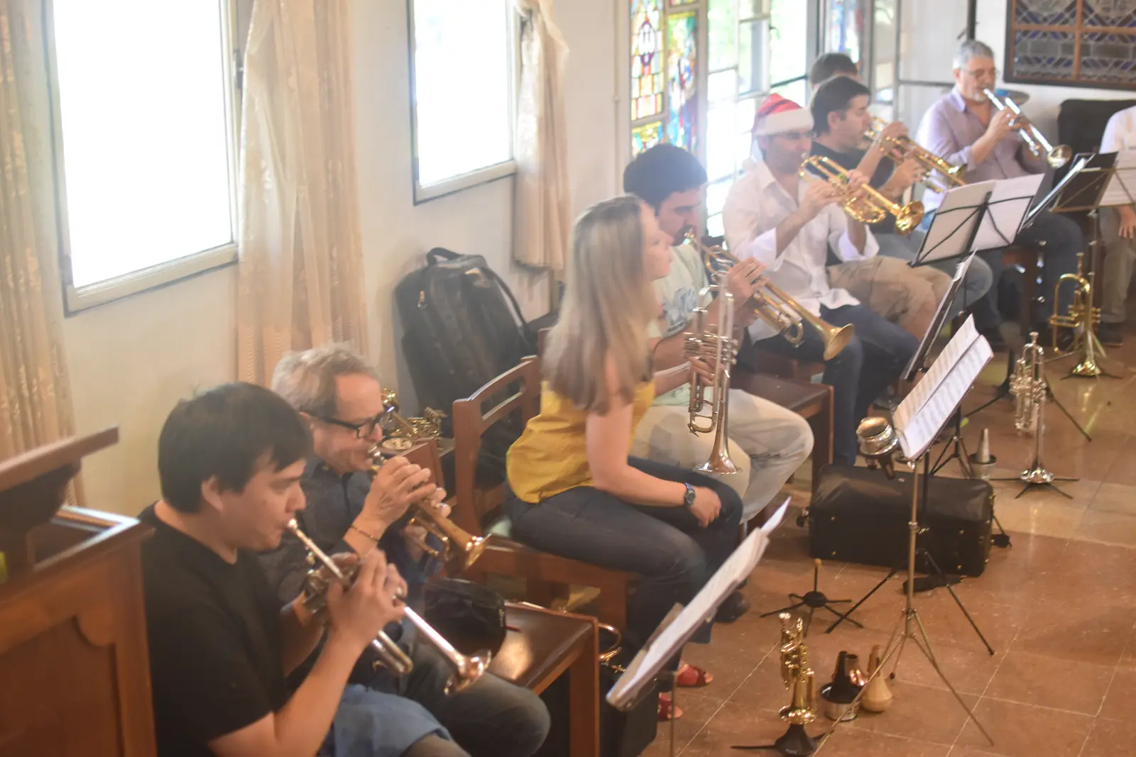 Fila de trompetistas tocando, con los instrumentos de repuesto en el piso