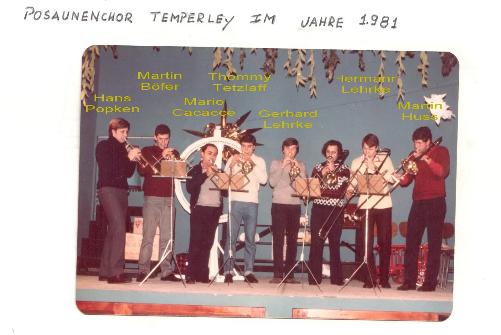Página de álbum rotulada Posaunenchor Temperley im Jahre 1981: ocho músicos tocando en un escenario decorado