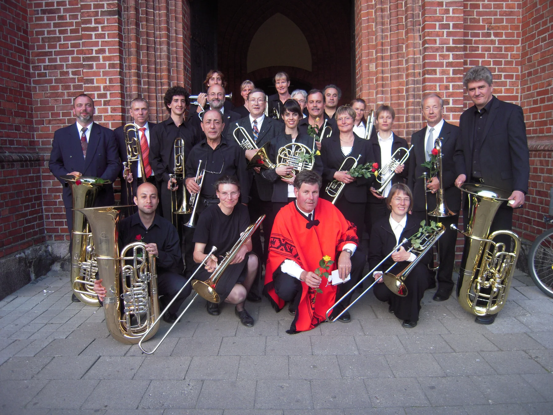 Las delegaciones de la gira posando juntas con sus instrumentos frente a una iglesia de Warnemünde