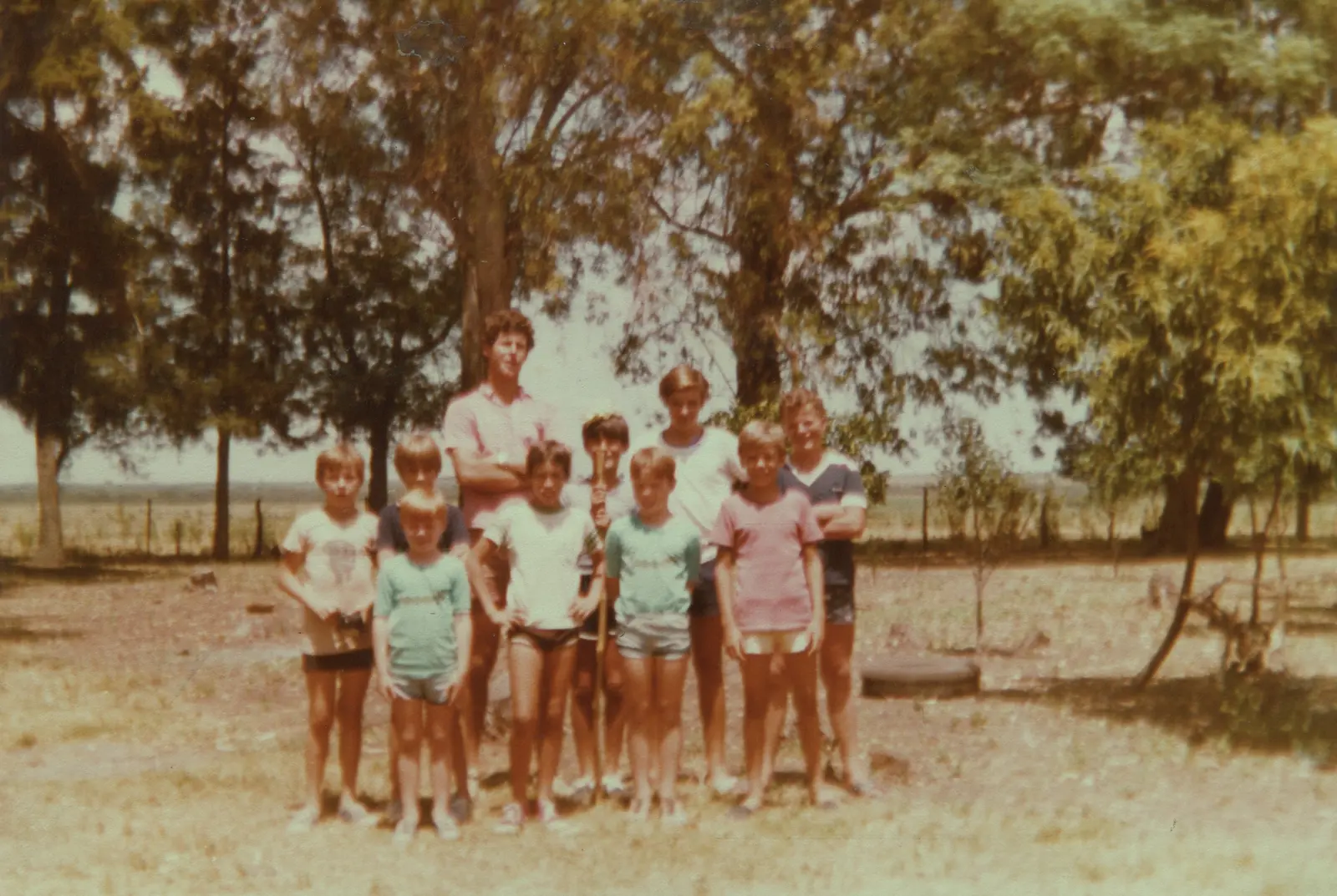 Martin Huss con diez chicos del coro bajo los árboles del campo en Macía, enero de 1983