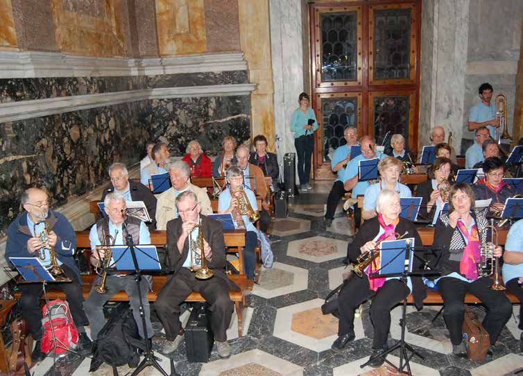 Los músicos sentados tocando con sus atriles sobre el piso de mármol de una capilla