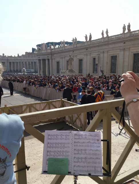 La Plaza de San Pedro llena de gente vista desde el puesto del conjunto, con un atril y la partitura en primer plano