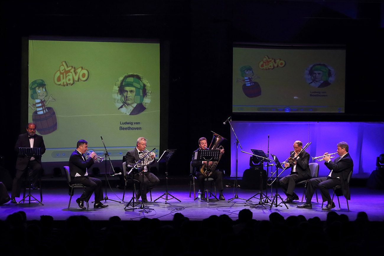 Das Quinteto Bronces del Plata spielt auf der Bühne, während zwei Leinwände die Zeichentrickfigur El Chavo neben einem Beethoven-Porträt mit der Mütze der Figur projizieren