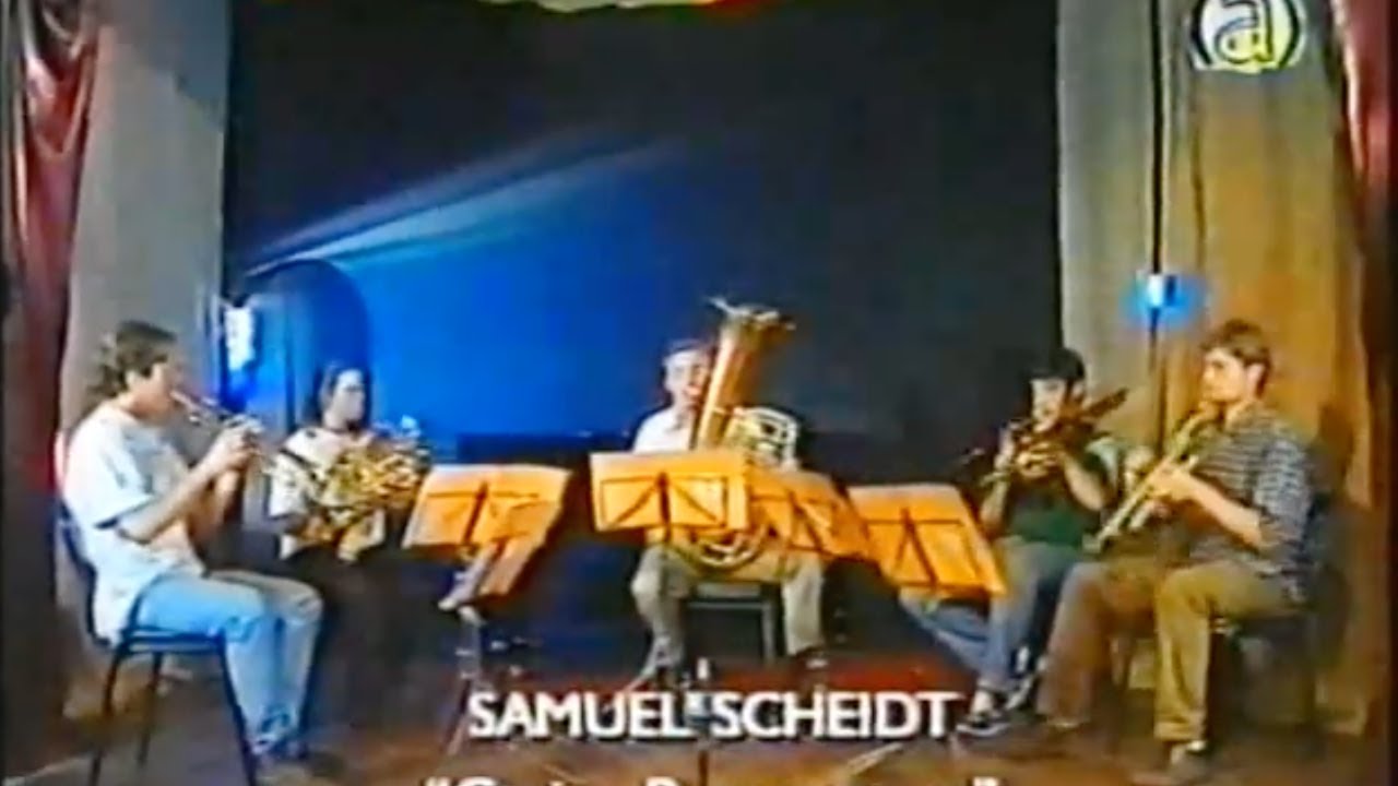 Videobild aus alter Zeit: fünf junge Musiker sitzen im Halbkreis an gelben Notenständern, der in der Mitte spielt Tuba, mit der eingeblendeten Schrift «Samuel Scheidt»