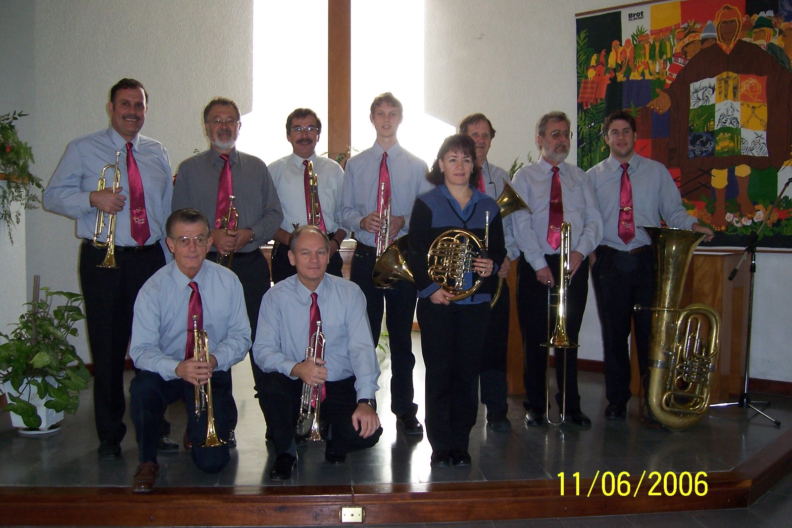 Formación de Olivos Brass posando con sus instrumentos en una iglesia; la fotografía lleva impresa la fecha 11/06/2006