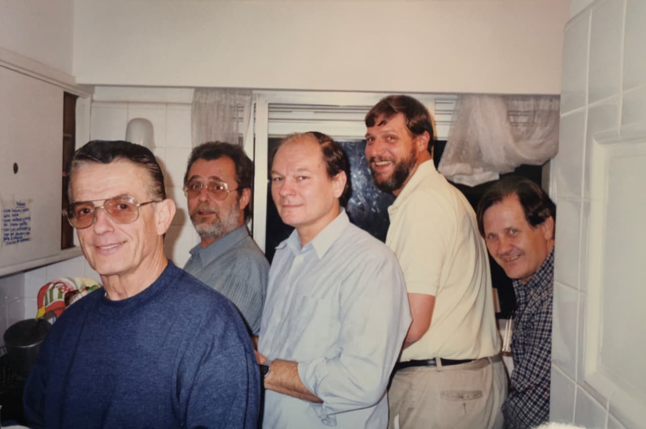 Cinco hombres sonrientes apretados en una cocina