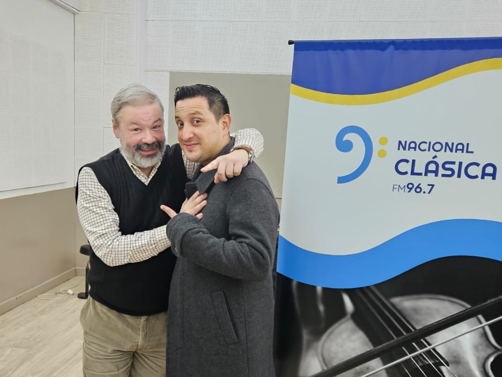 Richard Alonso Díaz, a la derecha, abrazado con el conductor Boris en el estudio de Nacional Clásica, junto al cartel de la emisora