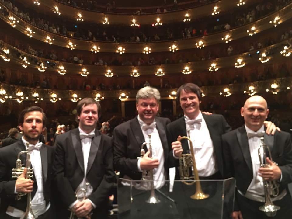 Cinco trompetistas de frac y moño blanco posan en la sala del Teatro Colón con sus instrumentos