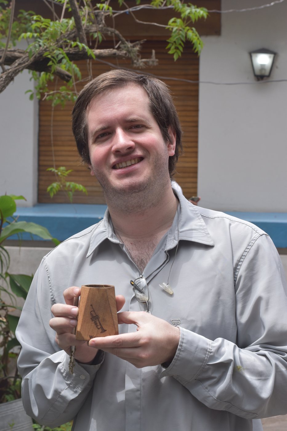 Werner Mengel sonríe mostrando un mate de madera con una trompeta grabada
