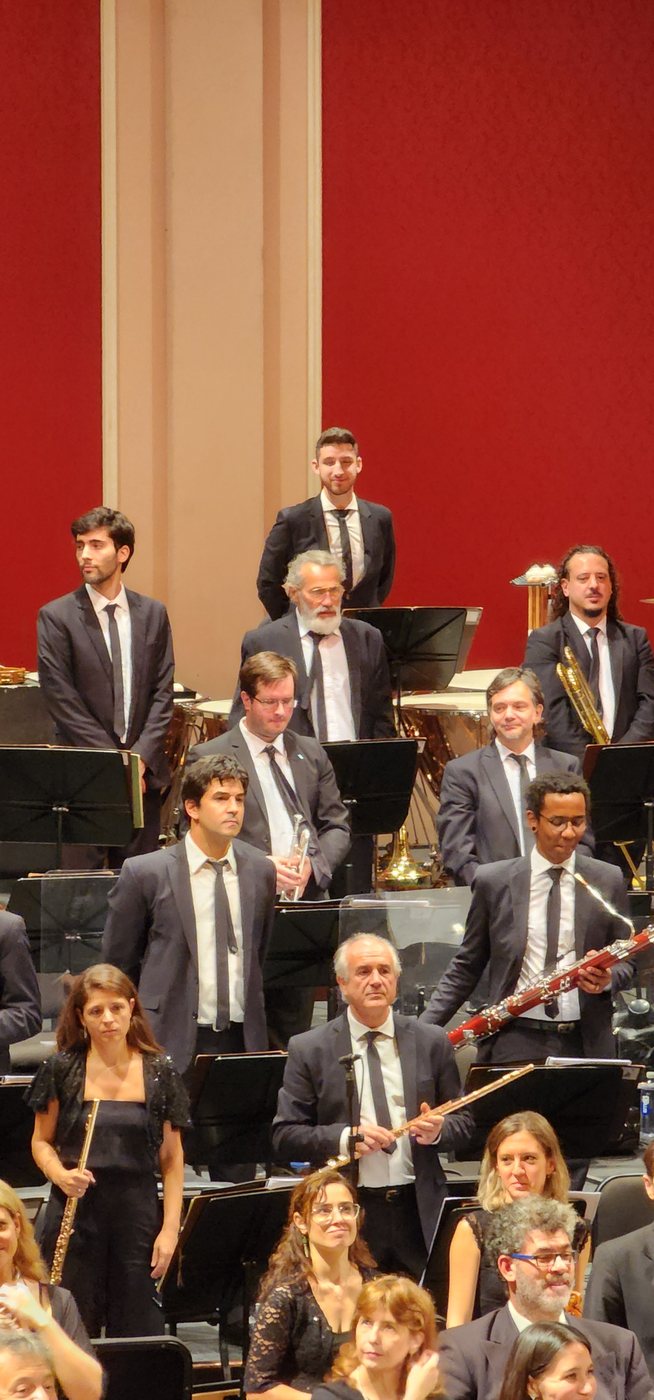 Músicos de la orquesta de pie en escena durante el saludo final, con Werner Mengel al centro con su trompeta