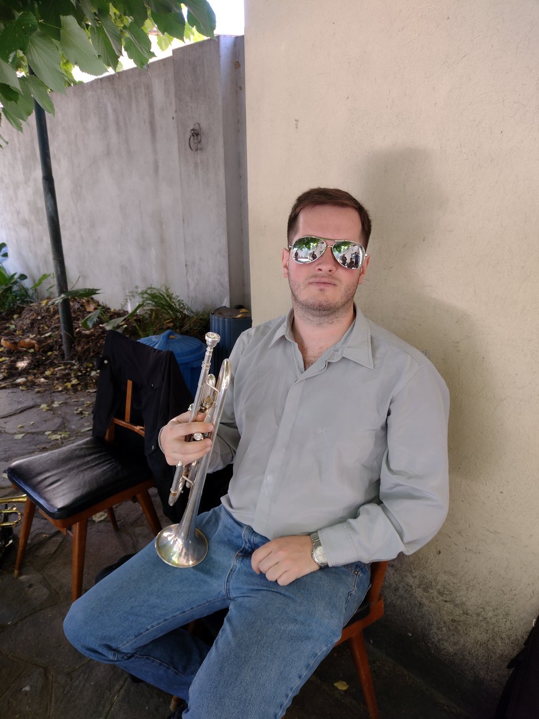 Werner Mengel con lentes de sol sostiene su trompeta plateada, en la iglesia con el coro