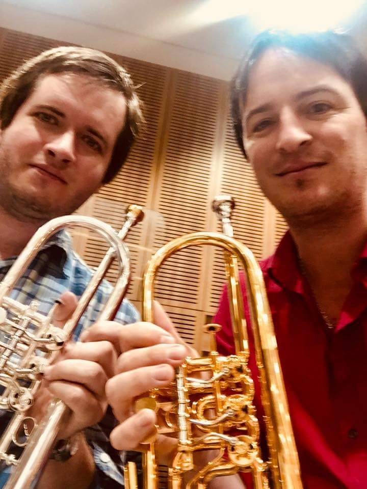 Selfie de Werner Mengel con un compañero de fila, ambos con sus trompetas, ante paneles acústicos de madera
